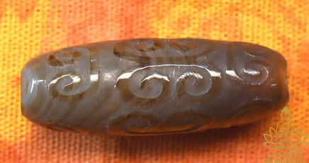 Perle tibétaine en agate sculptée à motifs sacrés La Magie du Bouddha.